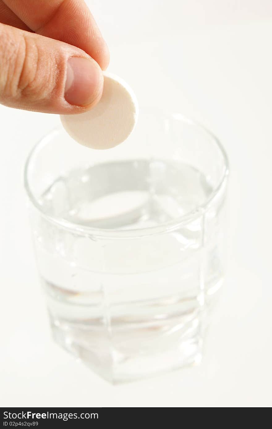 Tablet of sedative in a hand above a glass with water