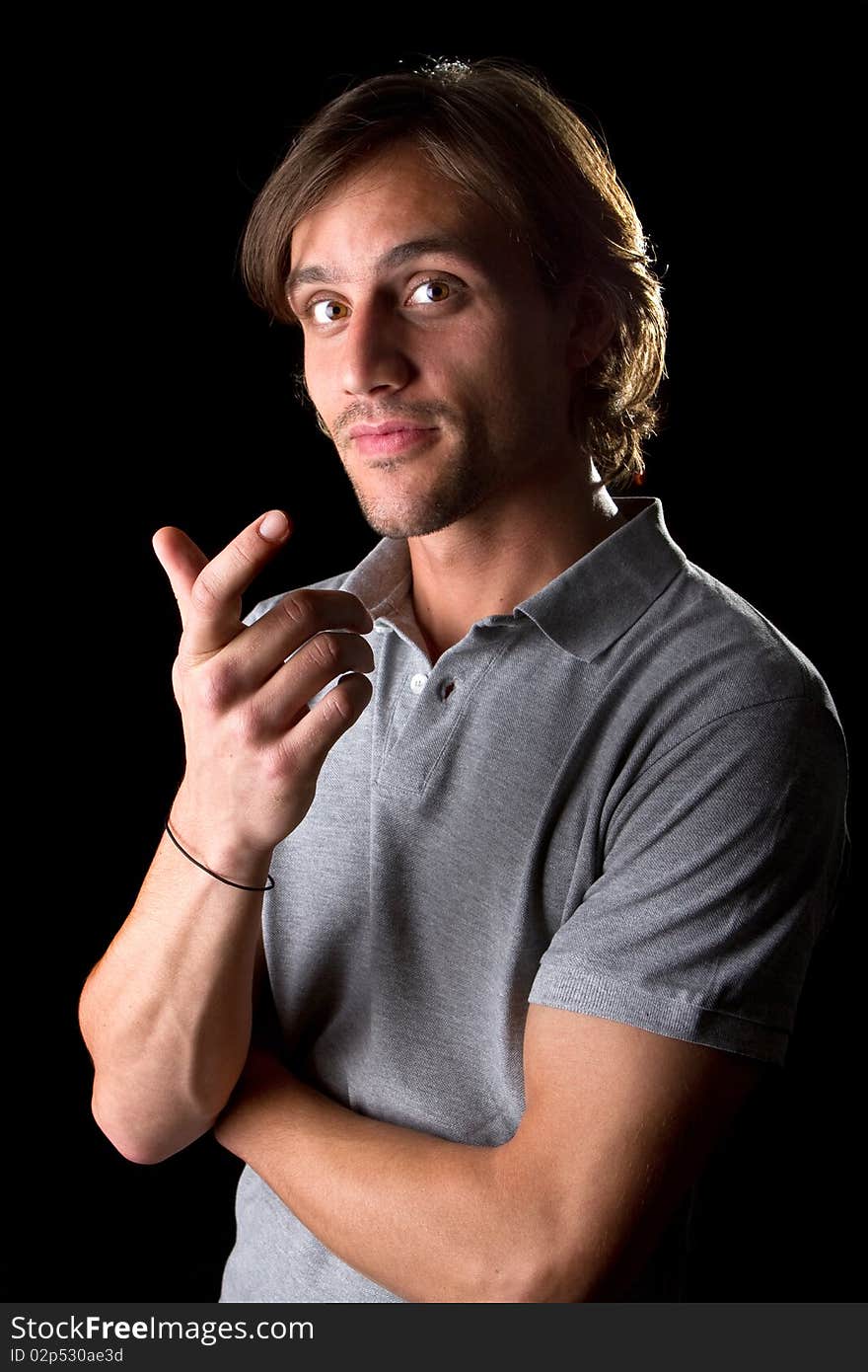 Young male model over black background with a grey shirt, with longer hair.