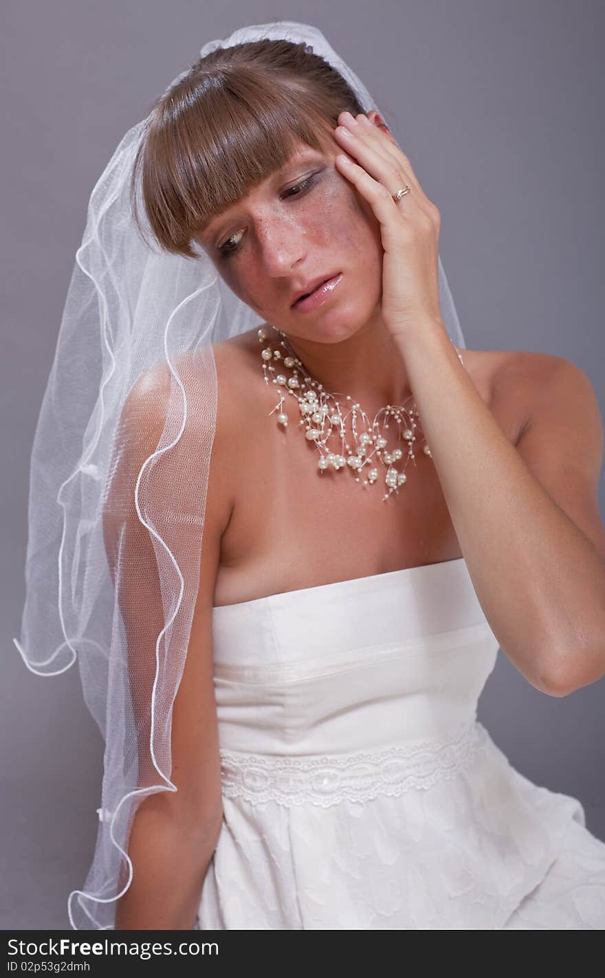 Portrait of crying bride over grey background