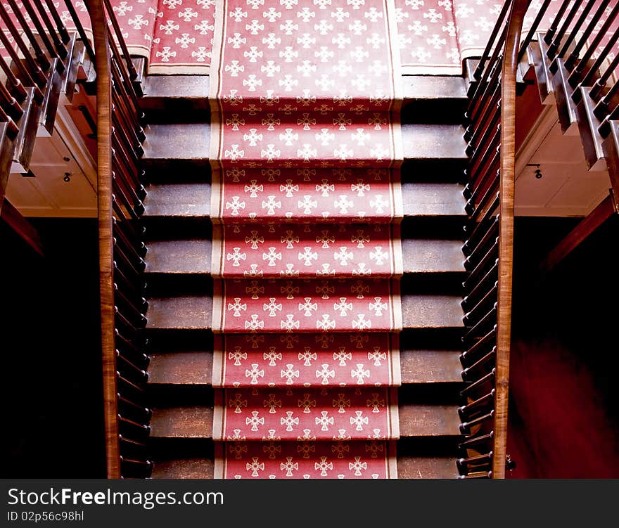 Old wooden imperial staircase with a red carpet