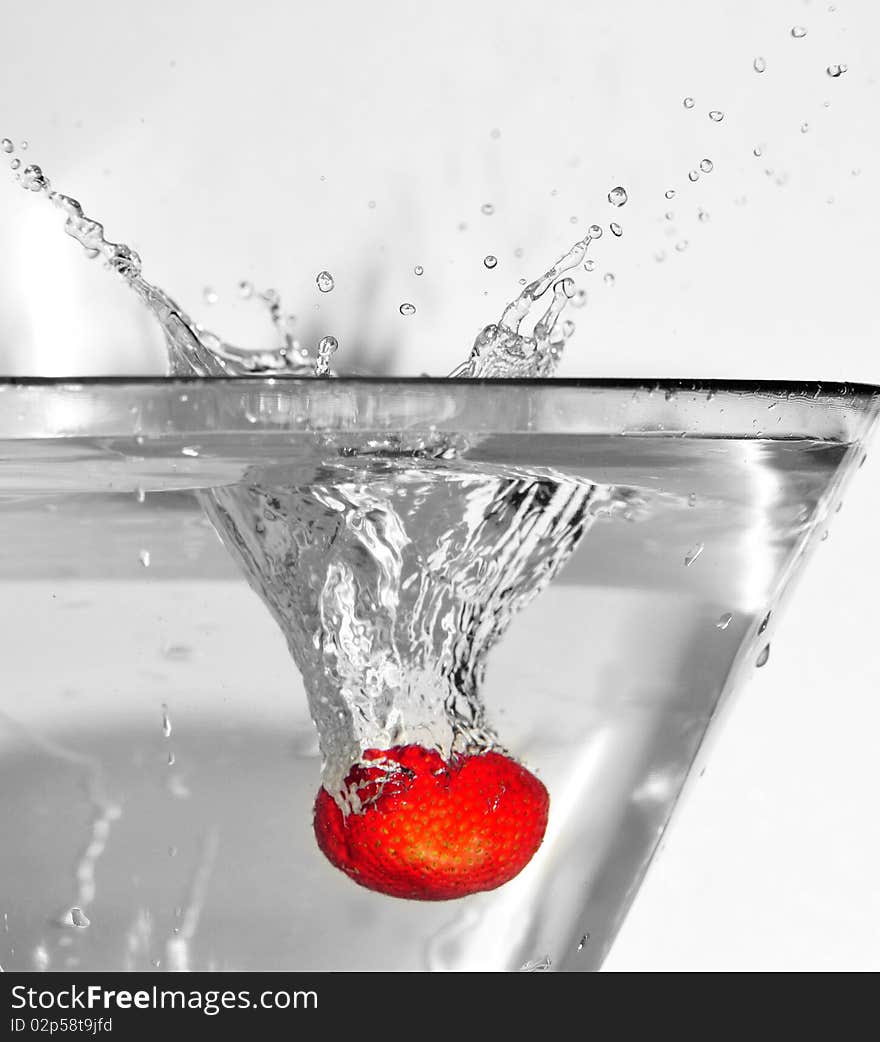 Strawberry falling into the water. Water droplets are emitted from the cup. Strawberry falling into the water. Water droplets are emitted from the cup