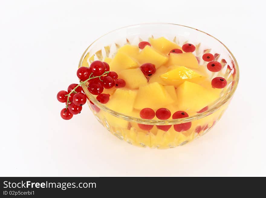 Peach compote with fresh red currants in glass bowl isolated on white