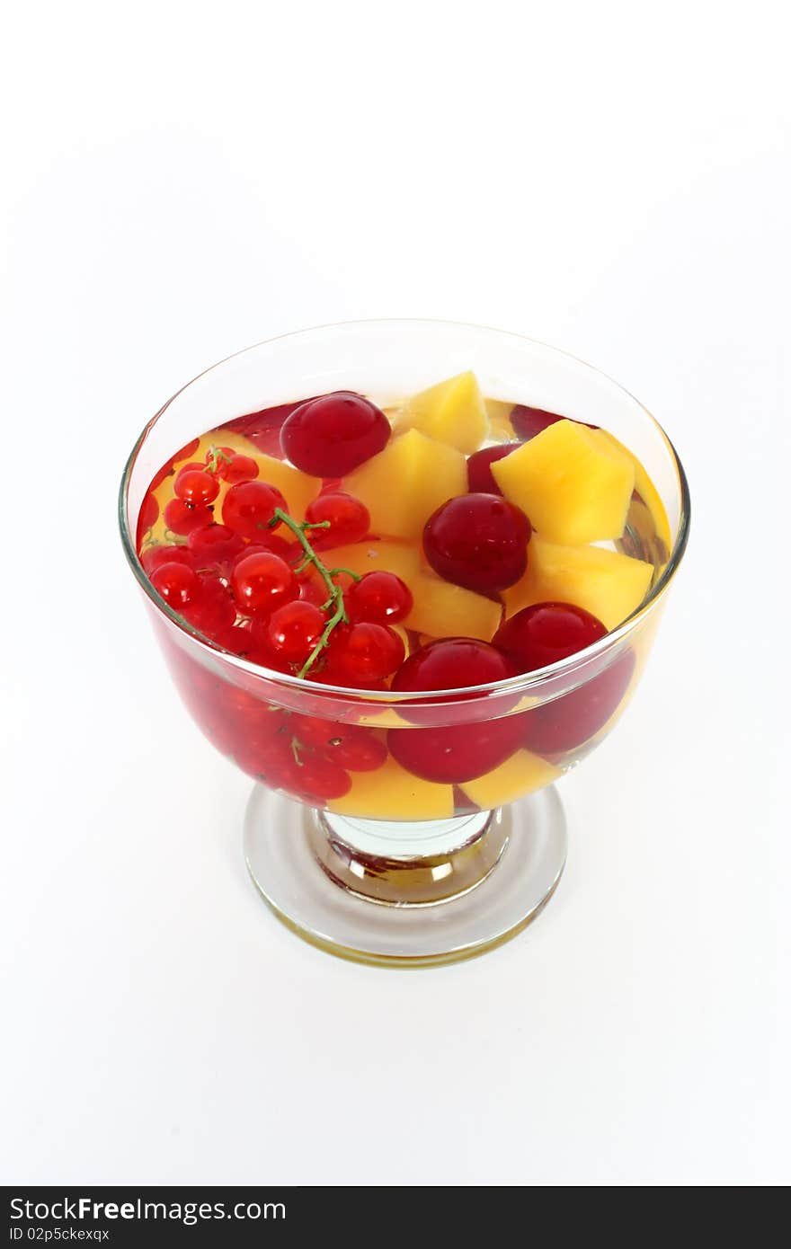 Peach compote with fresh red currants and sour cherries in glass bowl isolated on white