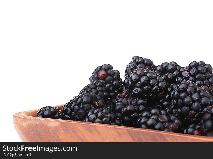 Blackberry - berries of black colour in a wooden plate on a white background. Blackberry - berries of black colour in a wooden plate on a white background.