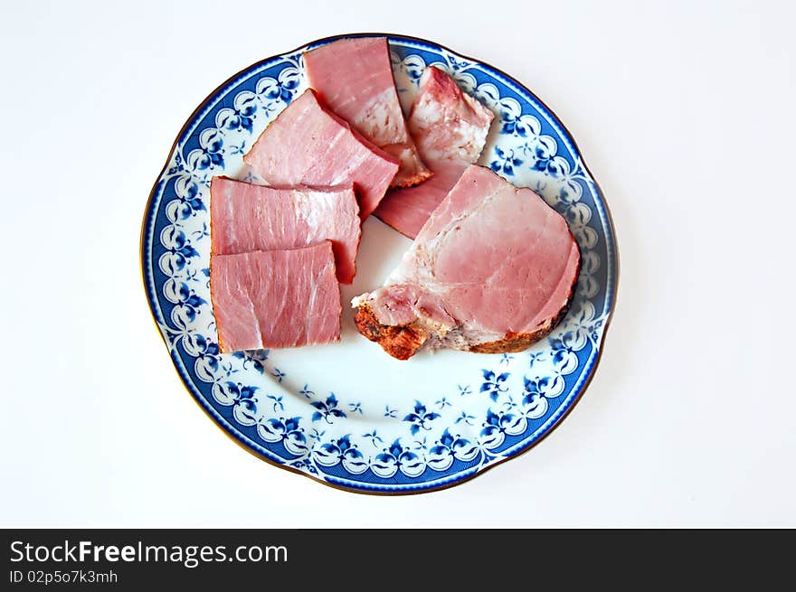 Ham sliced on a plate with a light shade on white background. Ham sliced on a plate with a light shade on white background