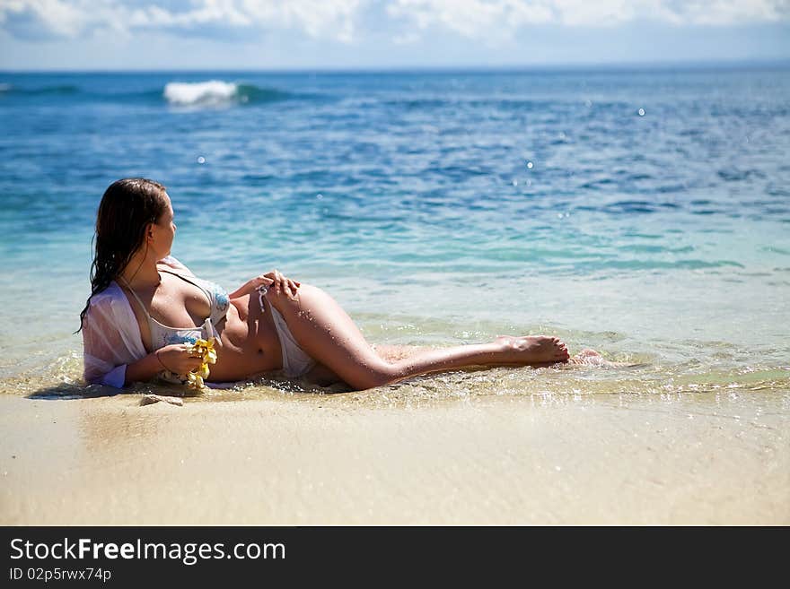 Young dark haired model lying in water on the beach. Young dark haired model lying in water on the beach