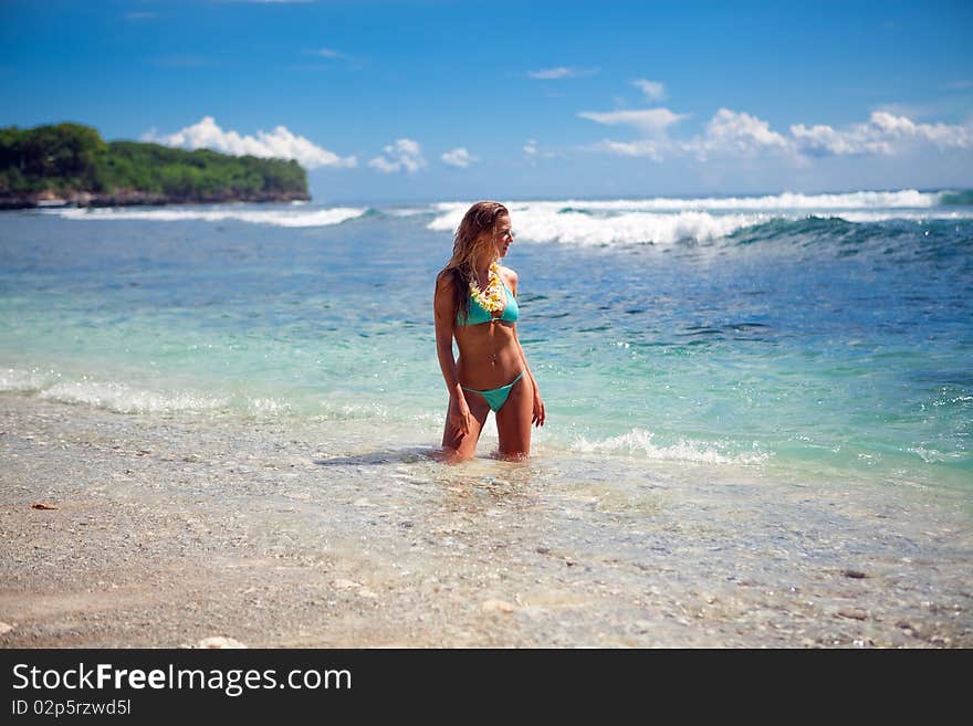 Young model blond girl standing in water on the beach