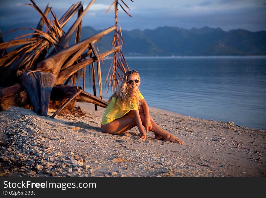 Young model blond girl sitting on the beach. Young model blond girl sitting on the beach