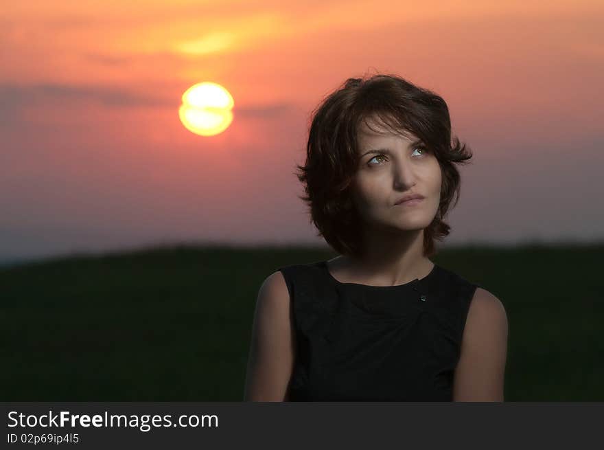 Photo of a young beautiful woman in a green wheat field at sunset. Photo of a young beautiful woman in a green wheat field at sunset