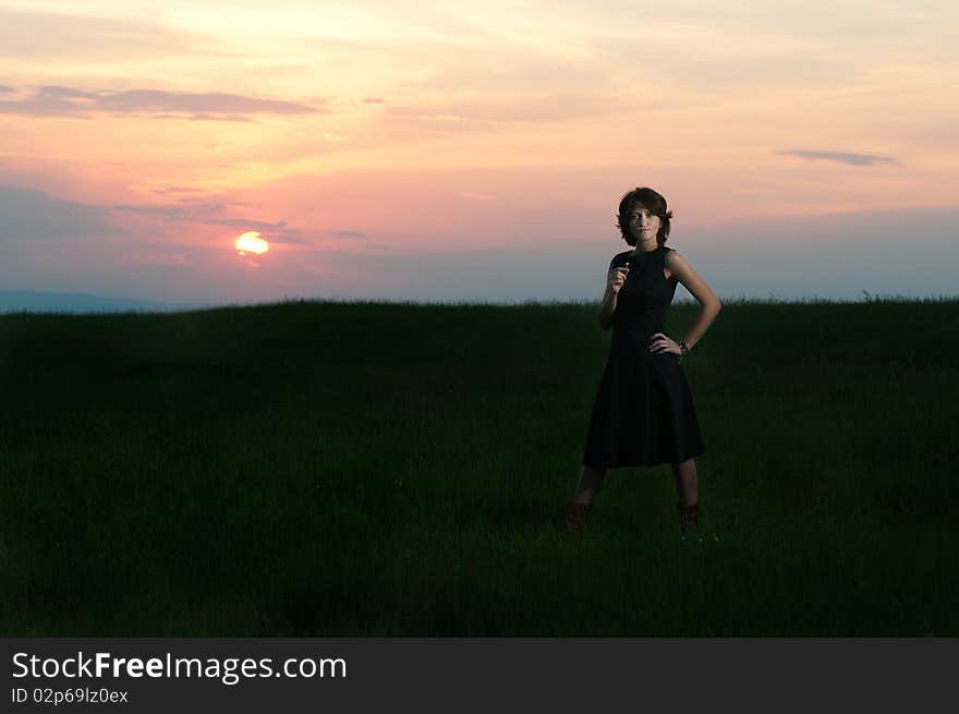 Photo of a young beautiful woman in a green wheat field at sunset. Photo of a young beautiful woman in a green wheat field at sunset