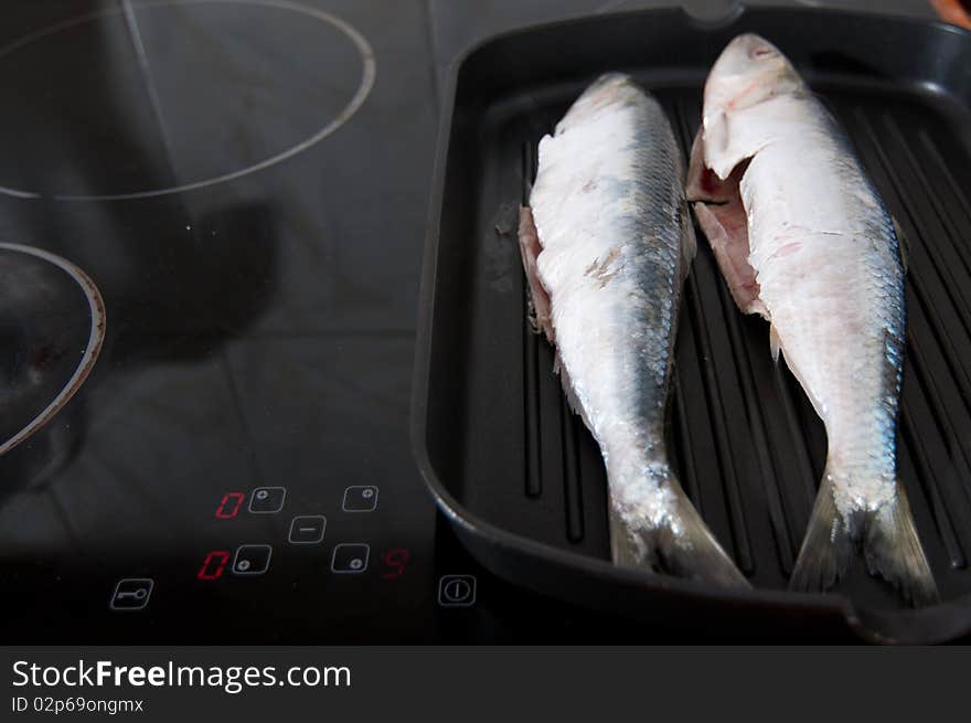 Two fishes cooked in a fry pan at maximum temperature. Two fishes cooked in a fry pan at maximum temperature