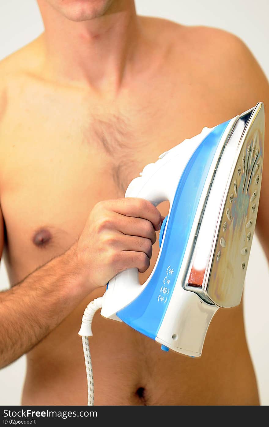 Naked man holding a blue and white clothing iron in front of hairy chest