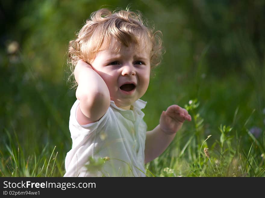 Little cute baby crying alone in the green grass. Little cute baby crying alone in the green grass