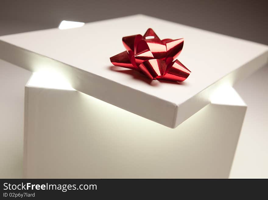 Gift Box with Red Bow Lid Revealing Very Bright Contents on a Gradated Background. Gift Box with Red Bow Lid Revealing Very Bright Contents on a Gradated Background.