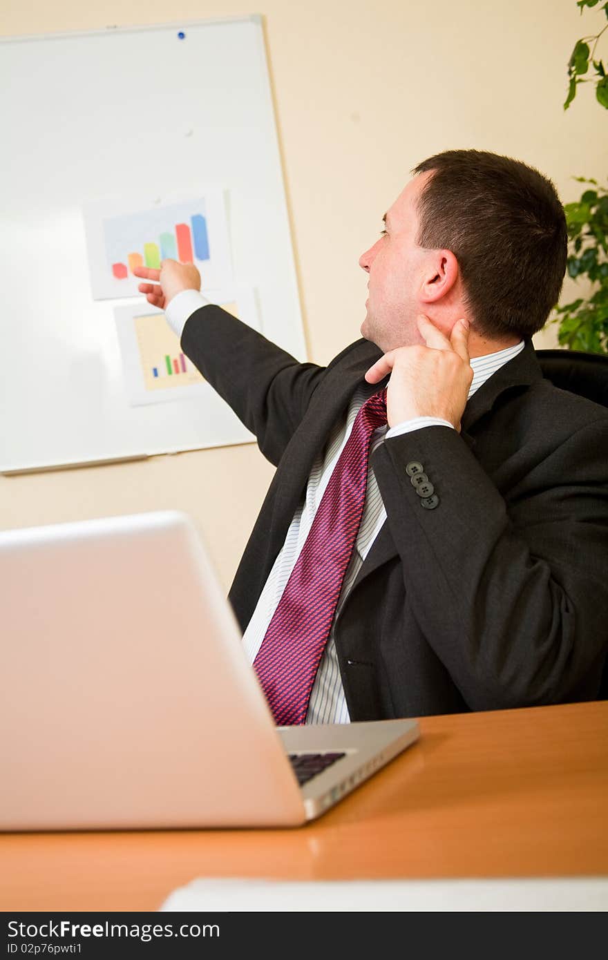 Business man pointing at whiteboard in office. Business man pointing at whiteboard in office