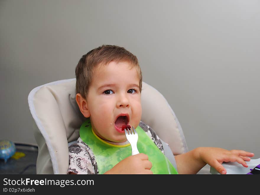 Baby boy trying eat with a little fork