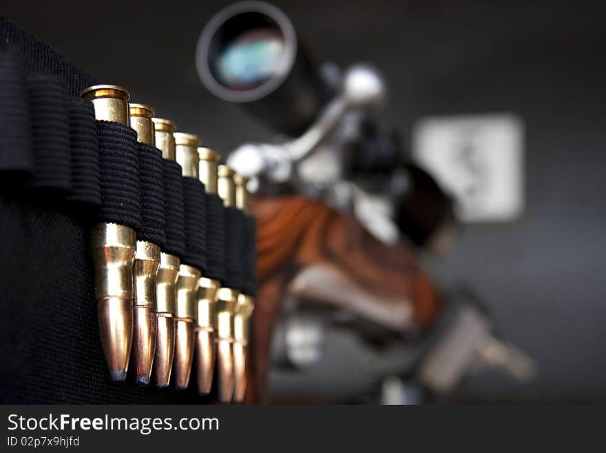 Closeup perspective shot of bullets mounted on gun stock with telescope, selective focus on ammunition. Closeup perspective shot of bullets mounted on gun stock with telescope, selective focus on ammunition