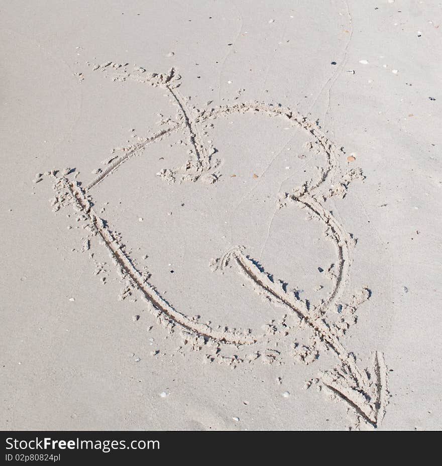 Cupid heart with an arrow in the sand