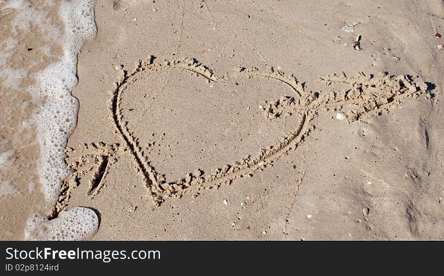 Cupid heart with an arrow in the sand