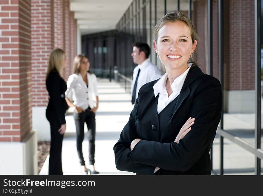 Attractive businesswoman with arms crossed and smiling with team behind