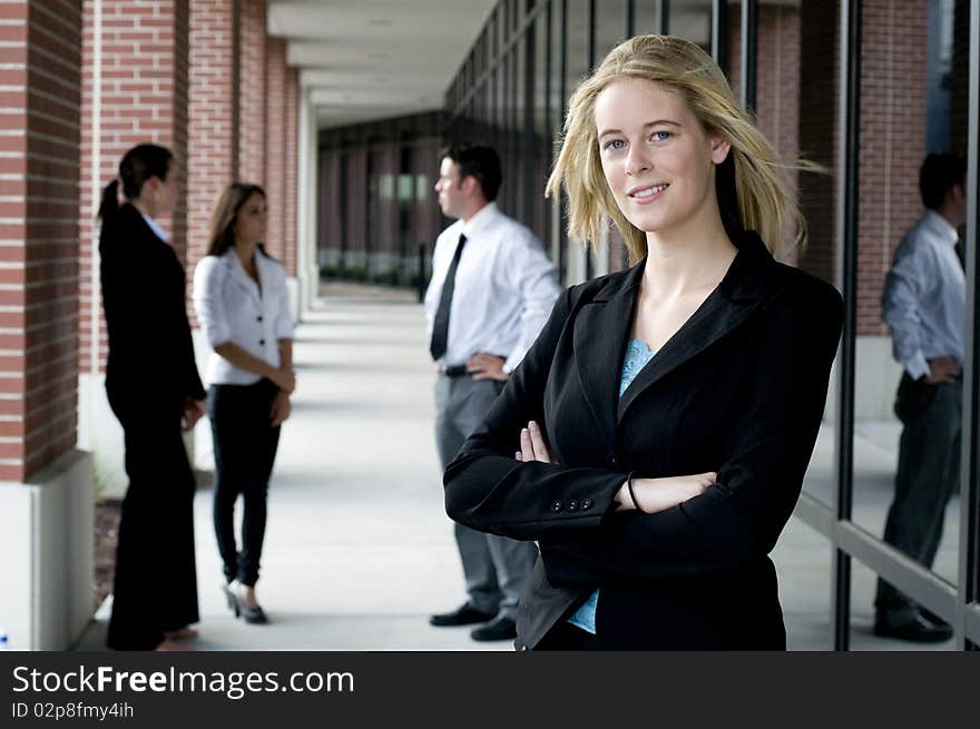 Attractive businesswoman with arms crossed and smiling with team behind