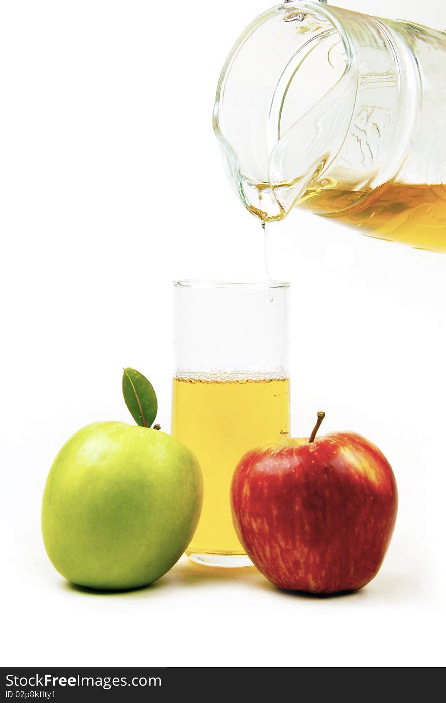 A glass of fresh apple juice with apples in the foreground