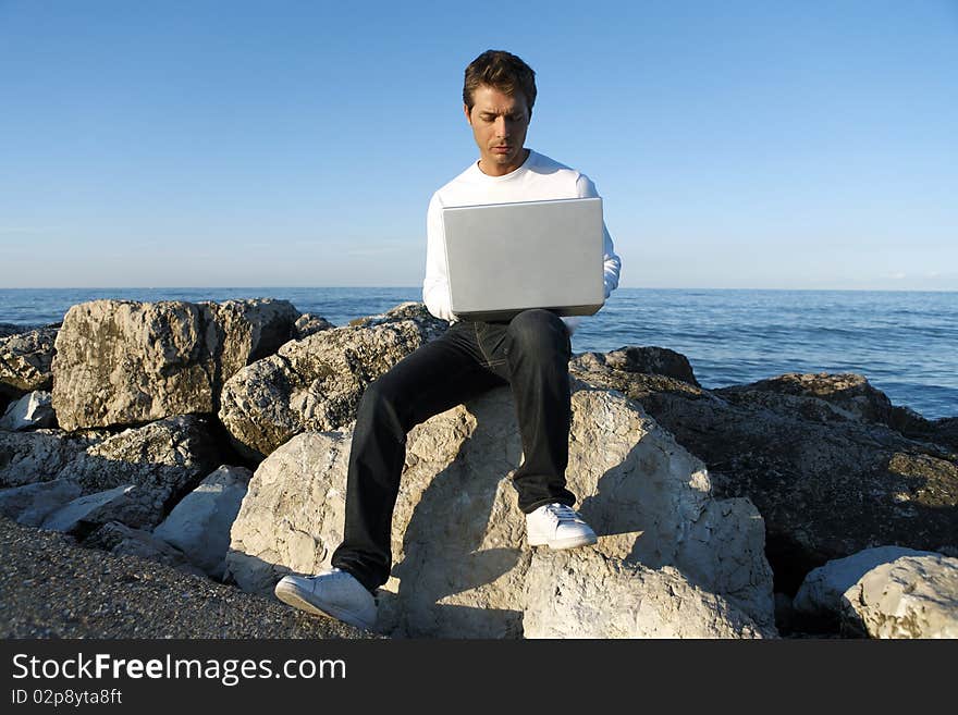 Young Man Using Laptop At Beach