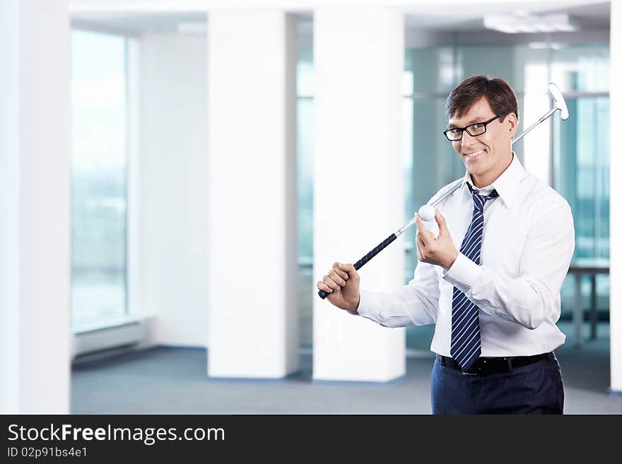 Business man with a golf club in office. Business man with a golf club in office