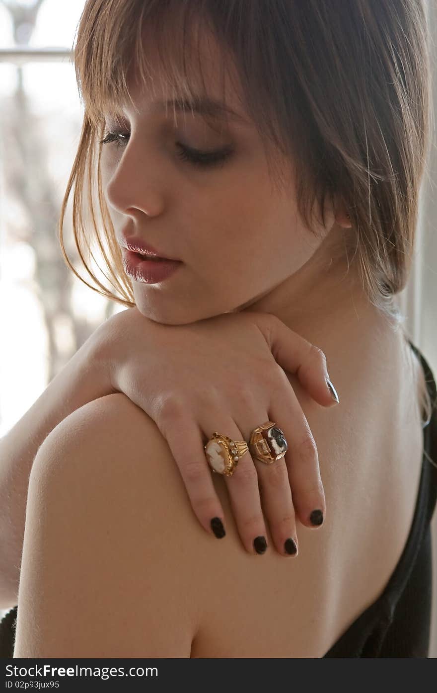 A classic portrait of a beautiful young woman with her hand on her bare shoulder. A classic portrait of a beautiful young woman with her hand on her bare shoulder