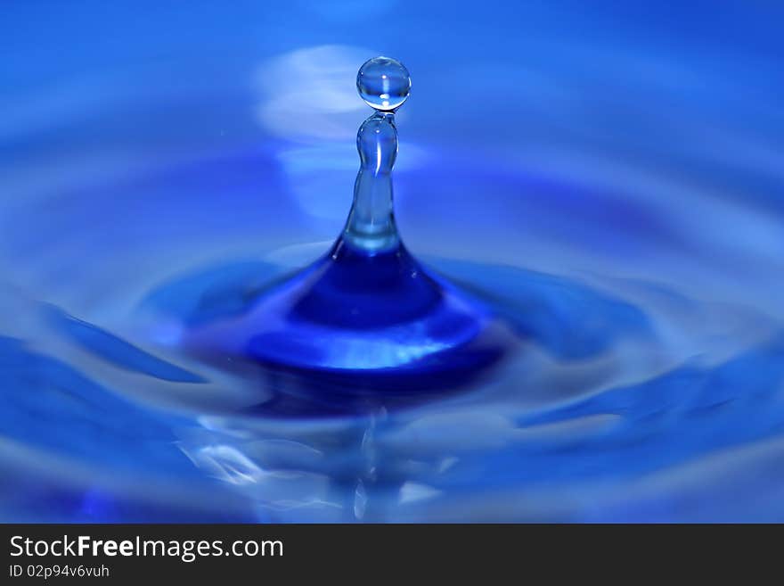 A blue water droplet splashing