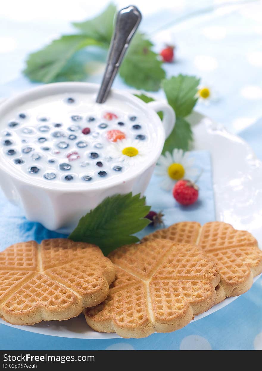 Cup of milk with cookies and berries for breakfast