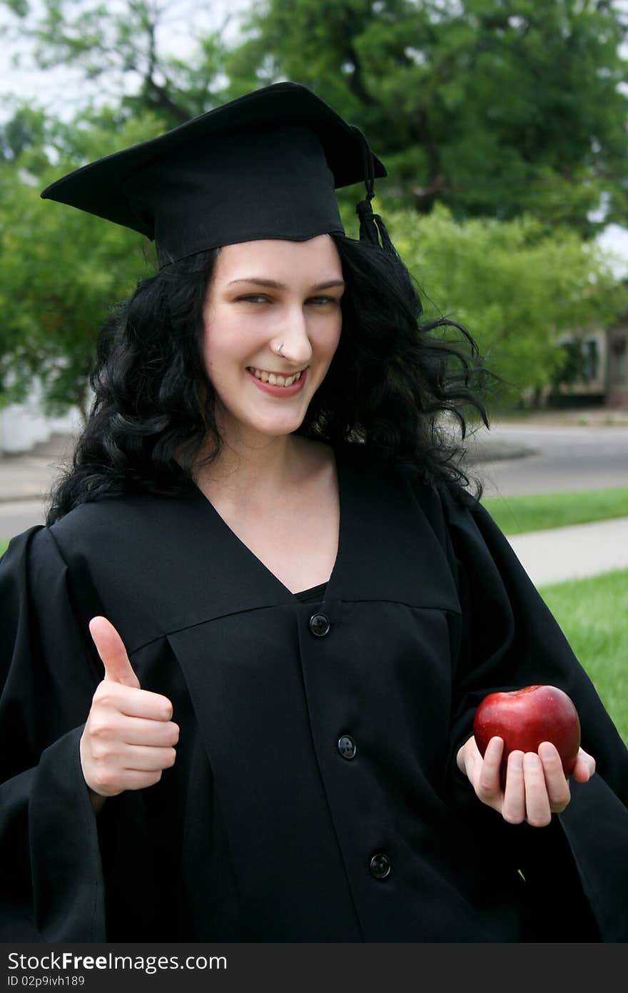 Caucasian student girl in gown with apple. Caucasian student girl in gown with apple