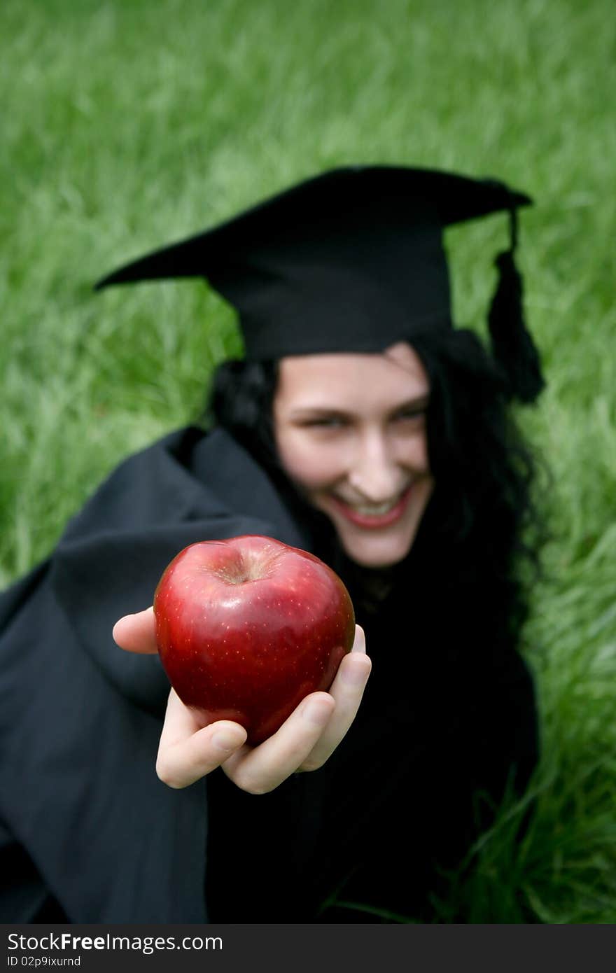 Young smiling caucasian student laying on the grass with apple. Young smiling caucasian student laying on the grass with apple