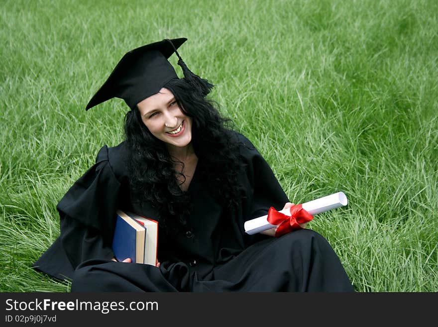 Happy bachelor with diploma on green lawn