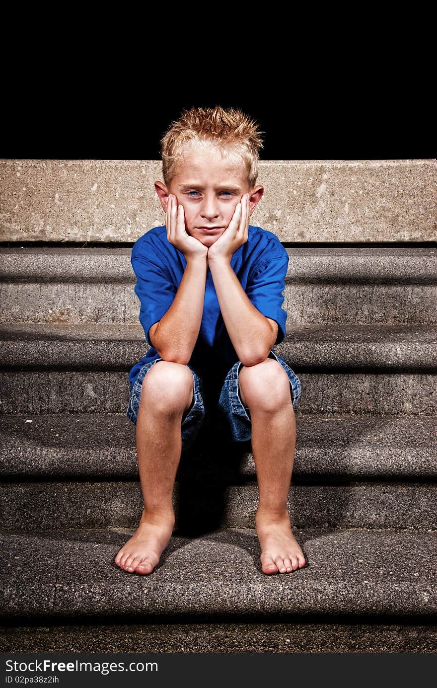 A young boy sitting on concrete steps