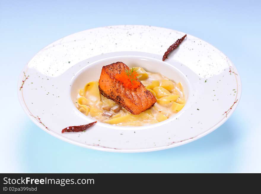 Fettuccine mushroom cream sauce with grilled salmon on blue background