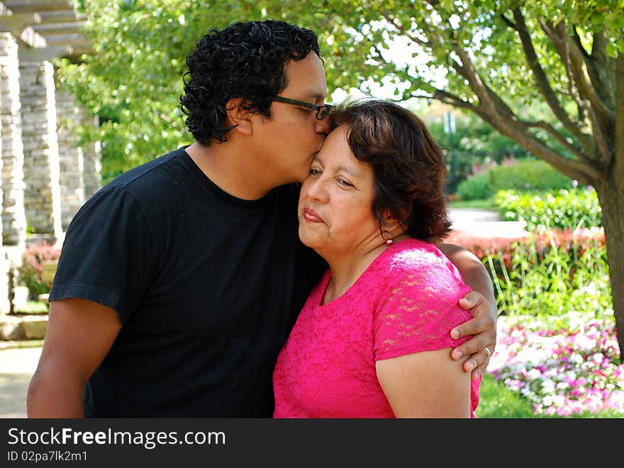 Hispanic man kissing his mother outdoors