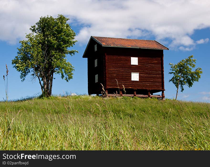 An old red wooden swedish barn on a hill with trees. An old red wooden swedish barn on a hill with trees.