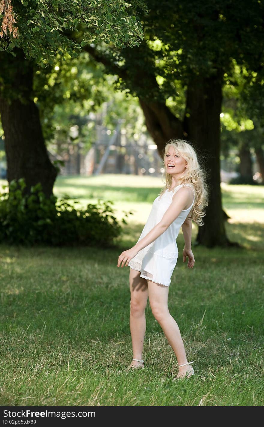 Young blond is dancing in her sundress under shadily trees in the park. Young blond is dancing in her sundress under shadily trees in the park