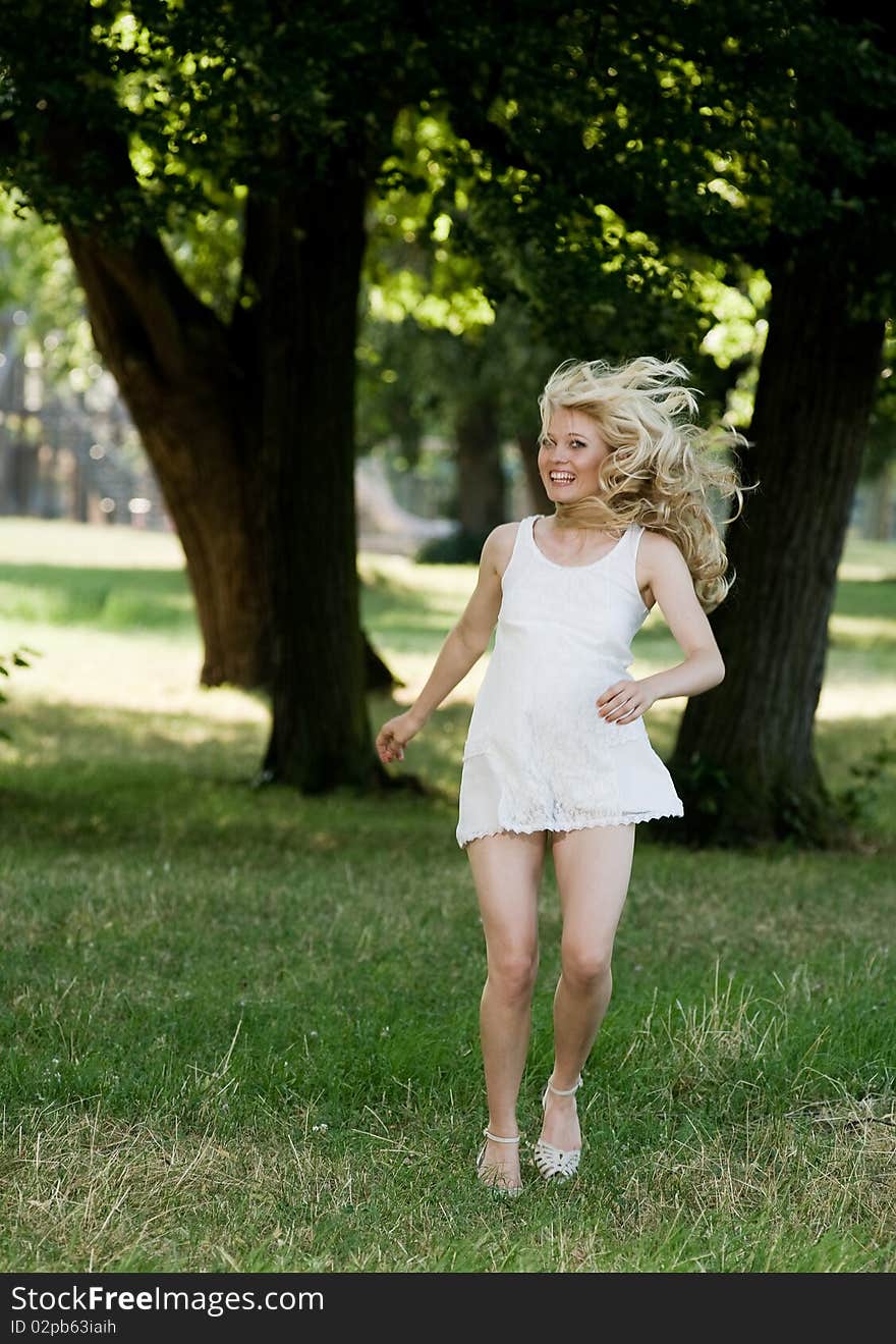 Young blond is dancing in her sundress under shadily trees in the park. Young blond is dancing in her sundress under shadily trees in the park