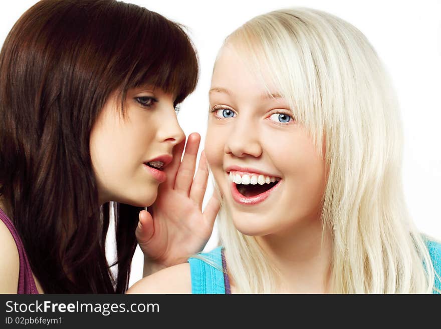 Two cute girls,one is whispering and the other is surprised about what she is hearing,isolated on white. Two cute girls,one is whispering and the other is surprised about what she is hearing,isolated on white