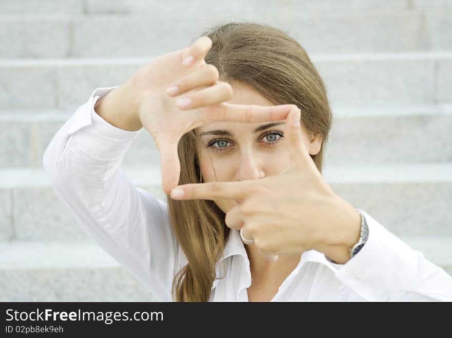 Young businesswoman looks through a frame made of hand. Young businesswoman looks through a frame made of hand