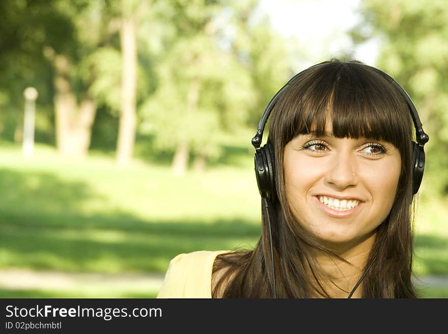 Smiling young woman listening to music at park