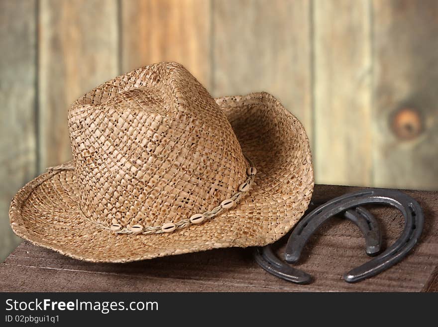 Old west scene with a cowboy hat and two horseshoes set against a wooden fence backdrop. Old west scene with a cowboy hat and two horseshoes set against a wooden fence backdrop.