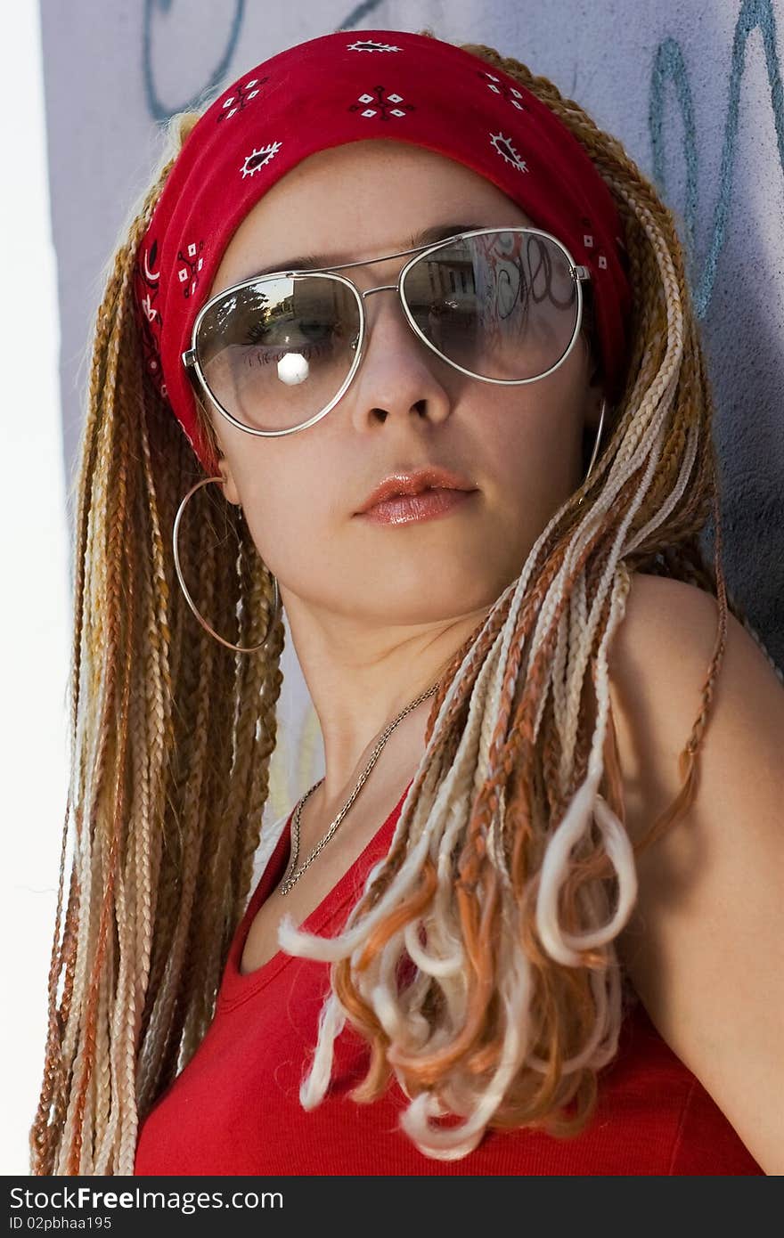 Hip-hop chick posing at the graffiti sprayed wall outdoors. Hip-hop chick posing at the graffiti sprayed wall outdoors