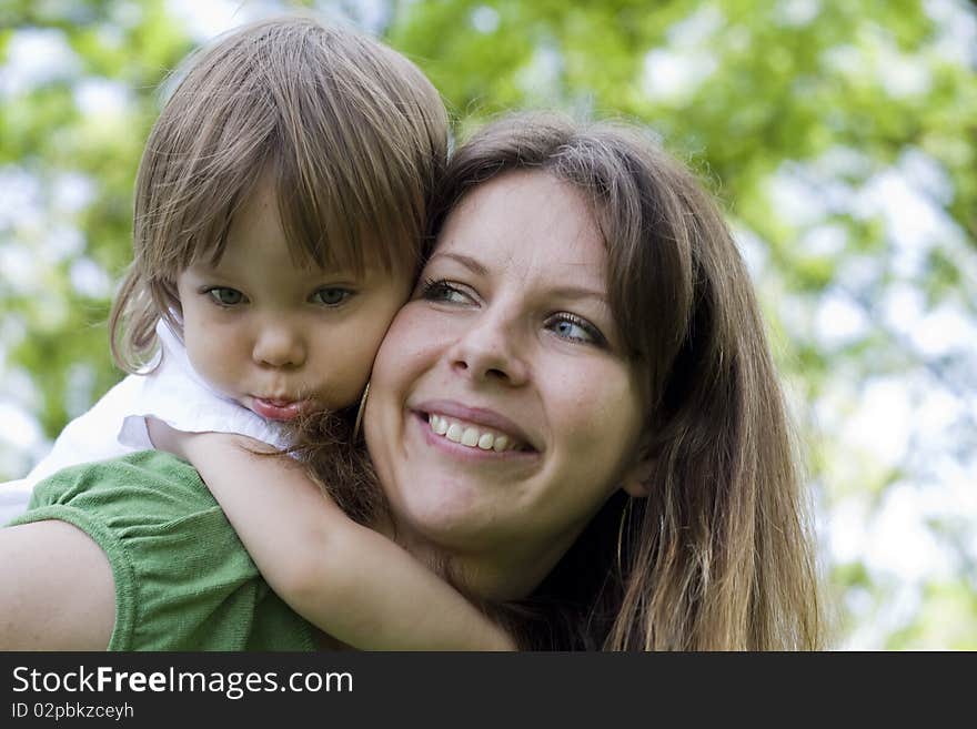 Mother holding daughter outdoors smiling