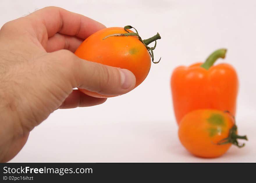 orange tomato and paprika in mans hand