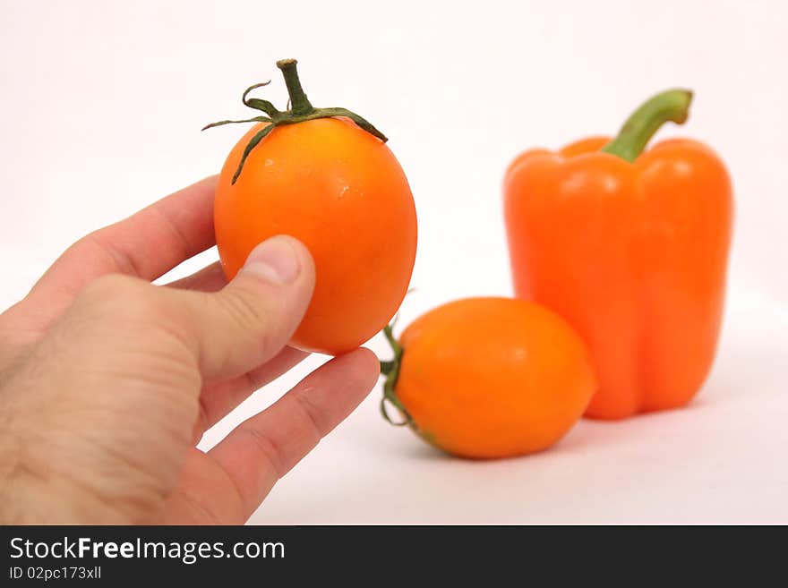 Orange tomato and paprika in mans hand