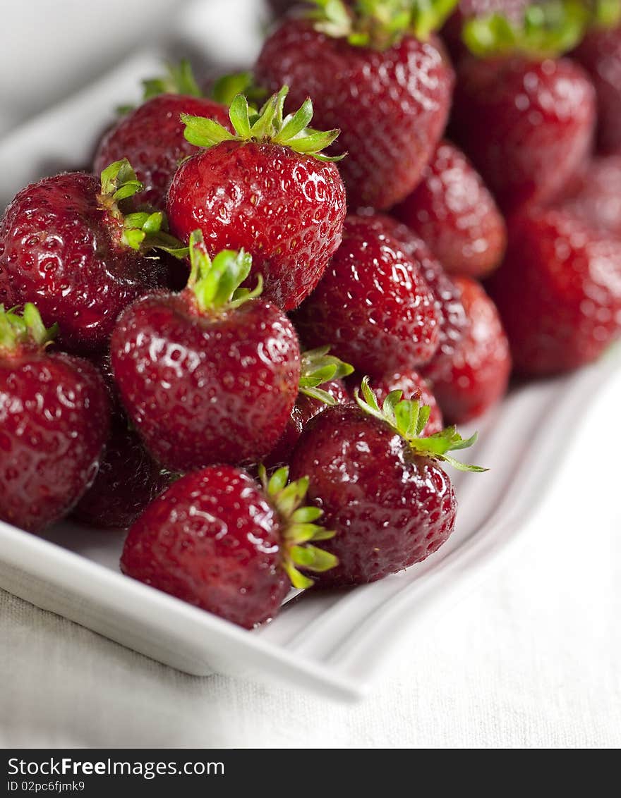 Luscious, fresh strawberries on a modern white platter. Shallow depth of field.