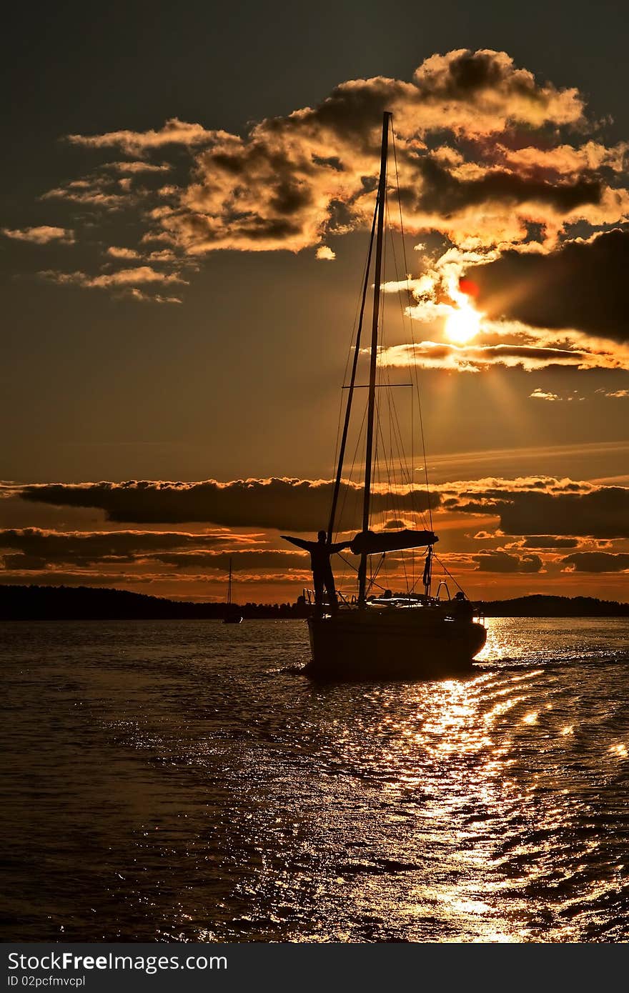 Yacht and sailor silhouette over coastline during sunset. Yacht and sailor silhouette over coastline during sunset.